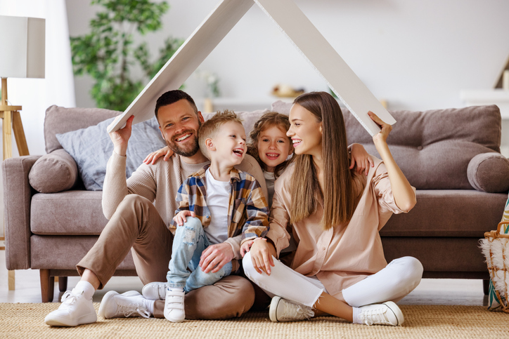 concept housing  young family. mother father and children under fake roof in  new home